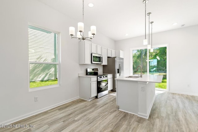 kitchen with an inviting chandelier, light countertops, a sink, light wood-style flooring, and stainless steel appliances