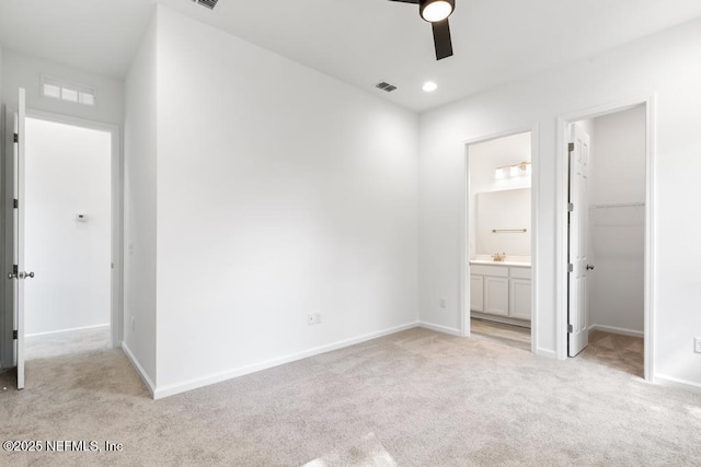 unfurnished bedroom with light carpet, baseboards, ensuite bathroom, a spacious closet, and a closet