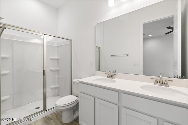 bathroom featuring toilet, a shower stall, a sink, and wood finished floors