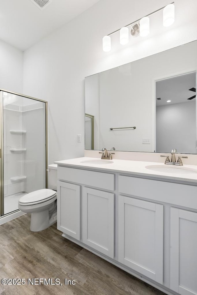 full bath with a stall shower, toilet, a sink, and wood finished floors