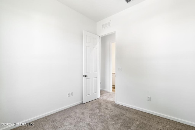 carpeted empty room featuring baseboards and visible vents