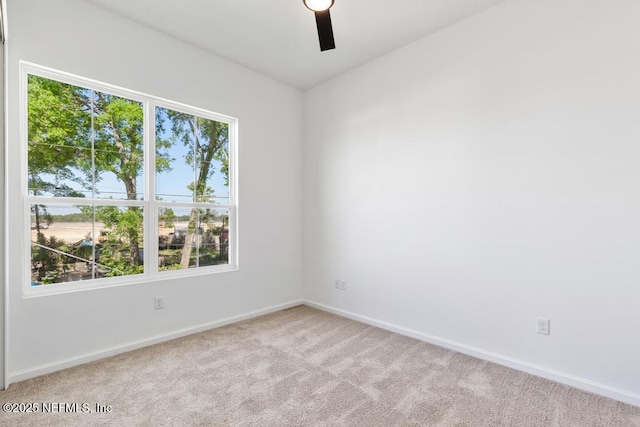 carpeted spare room featuring baseboards and ceiling fan