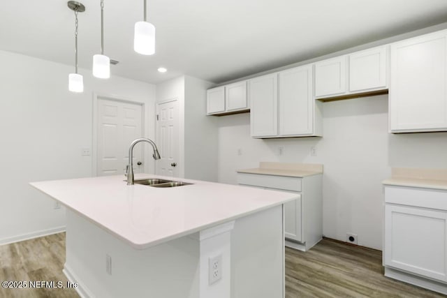 kitchen featuring a sink, light wood-type flooring, recessed lighting, pendant lighting, and an island with sink
