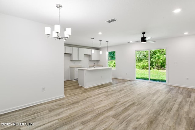 unfurnished living room with recessed lighting, light wood-style flooring, baseboards, and ceiling fan with notable chandelier