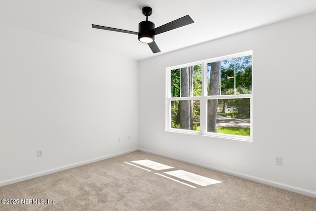 carpeted spare room featuring baseboards and ceiling fan