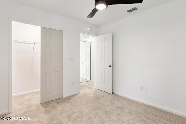 unfurnished bedroom featuring visible vents, baseboards, light colored carpet, a ceiling fan, and a closet