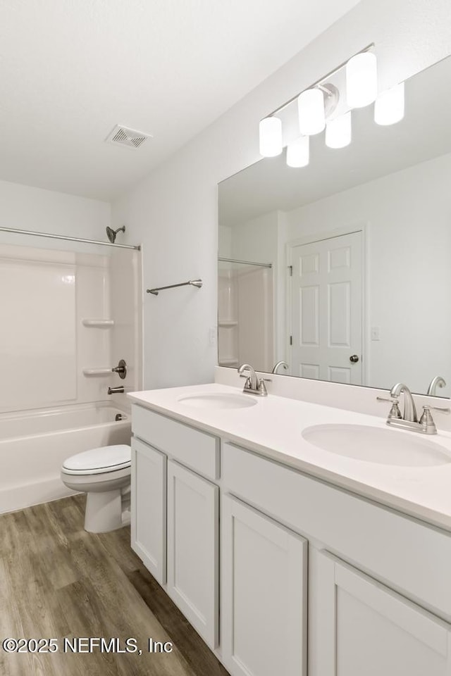 full bath featuring shower / bath combination, wood finished floors, a sink, and visible vents