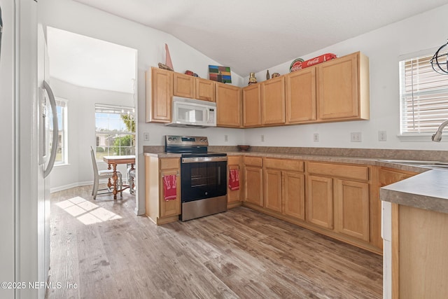 kitchen with a sink, light brown cabinetry, white appliances, light wood-type flooring, and lofted ceiling