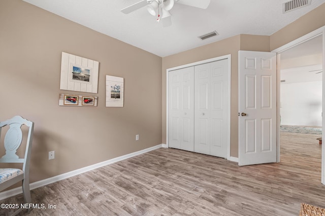 unfurnished bedroom with baseboards, wood finished floors, and visible vents