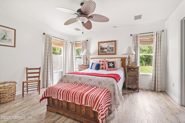 bedroom with wood finished floors, visible vents, baseboards, and multiple windows
