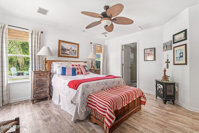 bedroom featuring wood finished floors, a wood stove, and multiple windows