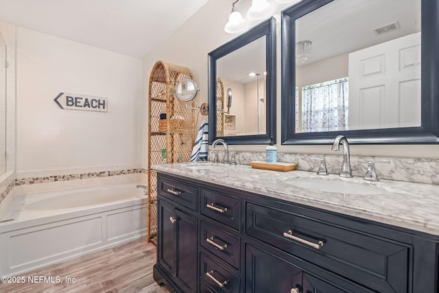 full bath featuring a bath, wood finished floors, a sink, and visible vents