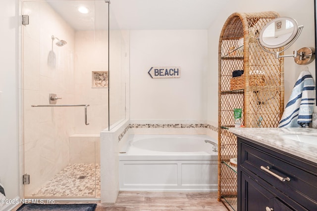 full bath with a shower stall, a bath, wood finished floors, and vanity