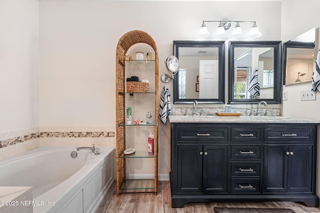 full bathroom featuring a garden tub, wood finished floors, a sink, and double vanity