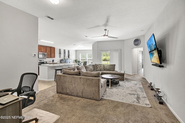living area featuring a textured ceiling, visible vents, ceiling fan, and light carpet