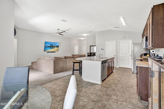 kitchen with a kitchen island with sink, a ceiling fan, vaulted ceiling, appliances with stainless steel finishes, and open floor plan