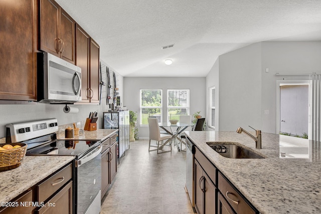 kitchen with visible vents, stainless steel appliances, light stone countertops, and a sink