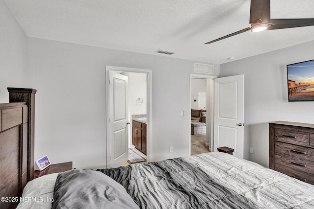 bedroom featuring a textured ceiling, visible vents, ceiling fan, and connected bathroom