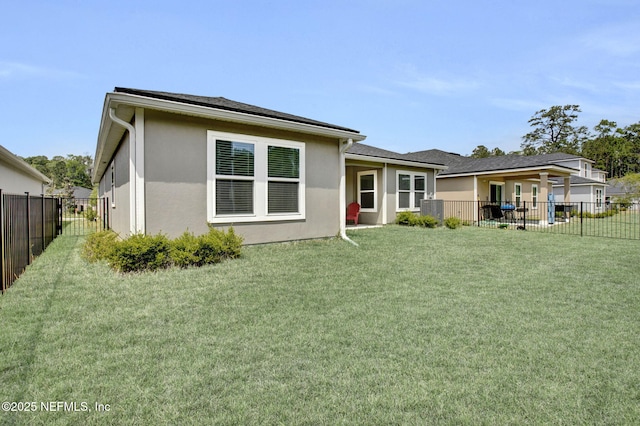 rear view of house featuring stucco siding, cooling unit, a yard, and a fenced backyard