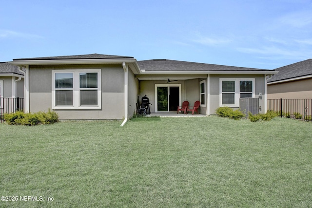 rear view of property with a patio, ceiling fan, a lawn, stucco siding, and fence