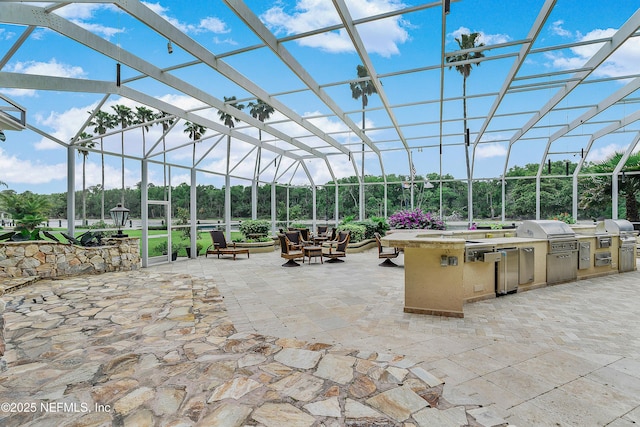view of patio / terrace featuring exterior kitchen, a grill, and glass enclosure