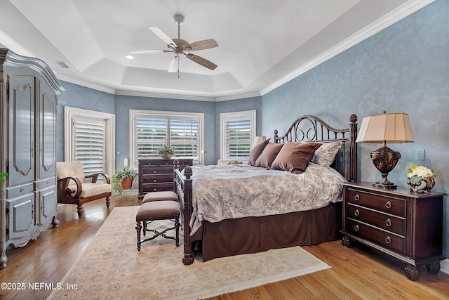 bedroom featuring a tray ceiling, wood finished floors, and a ceiling fan