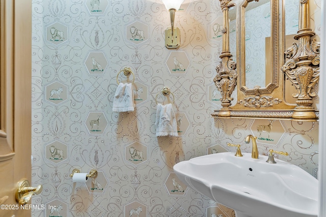 half bathroom featuring a sink and wallpapered walls