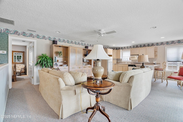living room featuring ceiling fan, light colored carpet, a textured ceiling, and recessed lighting