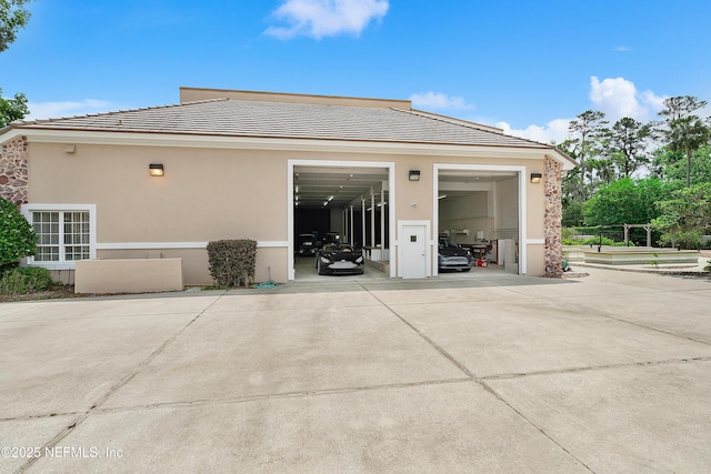 back of house with stucco siding, concrete driveway, and a tiled roof