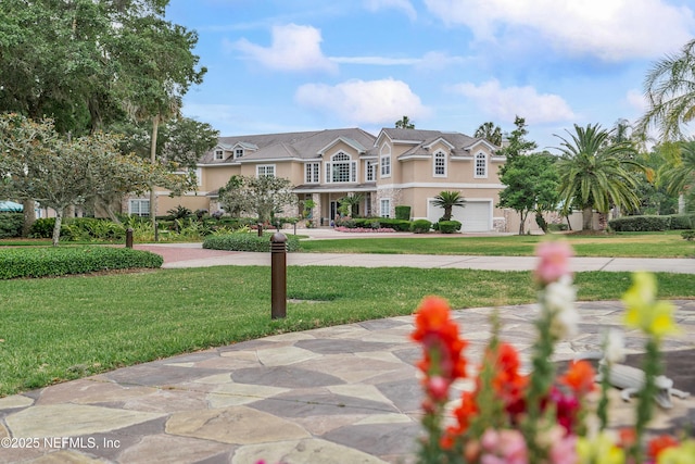 view of front of property with stucco siding, driveway, a garage, a front yard, and stone siding
