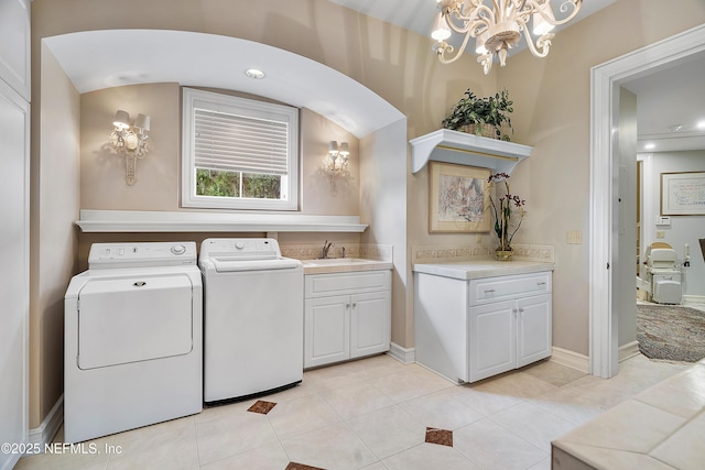 clothes washing area featuring washer and clothes dryer, cabinet space, a chandelier, light tile patterned floors, and baseboards