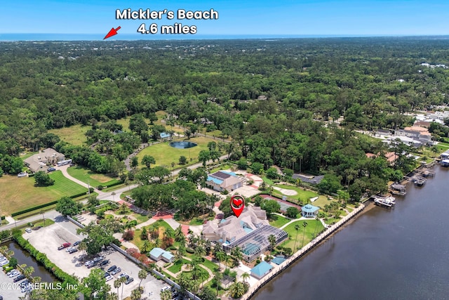 aerial overview of property's location featuring a heavily wooded area and a nearby body of water