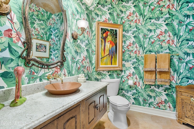 bathroom featuring wallpapered walls, baseboards, toilet, and vanity