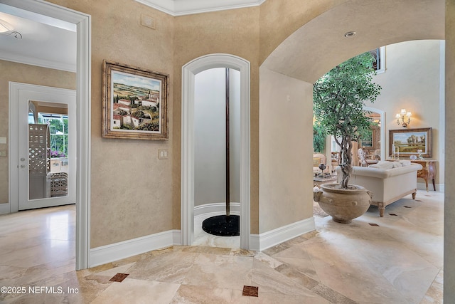 hall featuring arched walkways, ornamental molding, marble tiled flooring, and baseboards