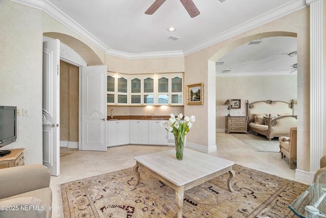 living room with a ceiling fan, arched walkways, crown molding, and baseboards