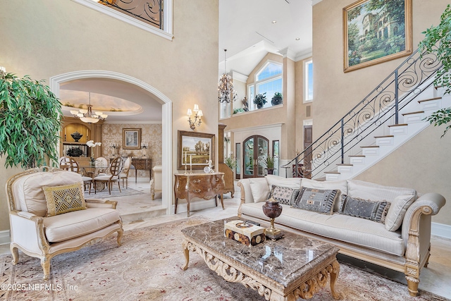 living area featuring a chandelier, a high ceiling, baseboards, stairway, and arched walkways