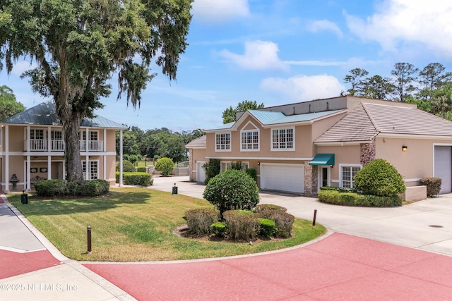 view of front of home featuring stucco siding, driveway, a front lawn, a garage, and metal roof