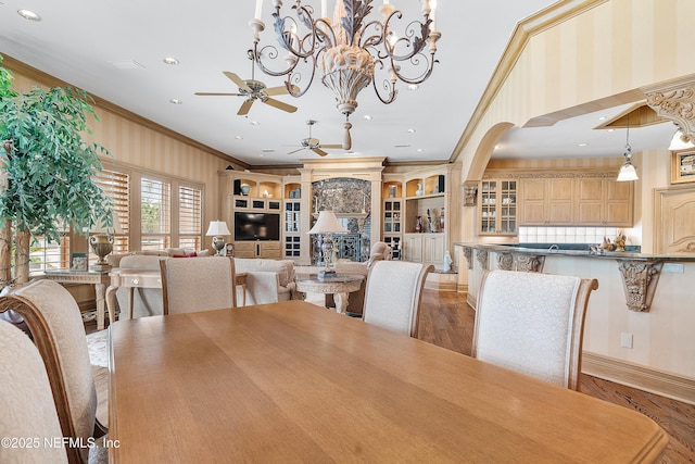 dining space featuring ceiling fan, ornamental molding, wood finished floors, arched walkways, and recessed lighting