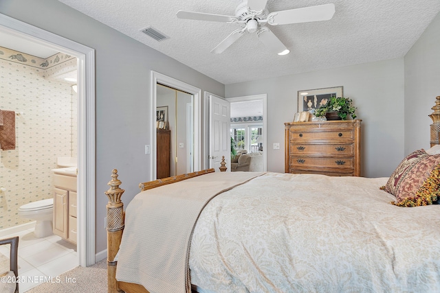 bedroom with a textured ceiling, ensuite bath, a closet, a ceiling fan, and baseboards