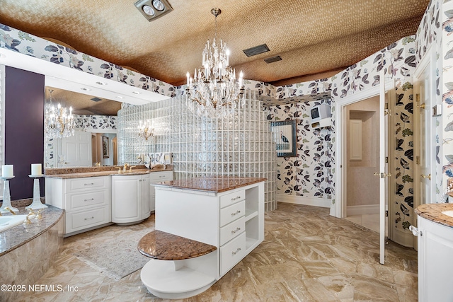 bathroom with a chandelier, vanity, a bathtub, and wallpapered walls