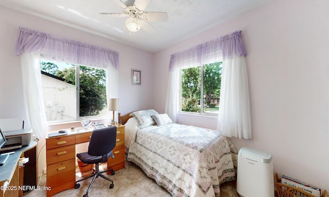 bedroom with a ceiling fan, light colored carpet, and multiple windows