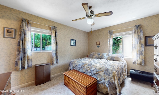 carpeted bedroom with a ceiling fan and wallpapered walls