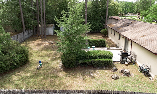 view of yard with fence, a storage unit, and an outbuilding