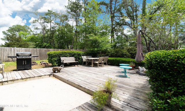 wooden deck with fence, outdoor dining area, and a grill
