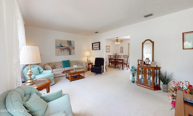 living room featuring visible vents, a ceiling fan, and carpet