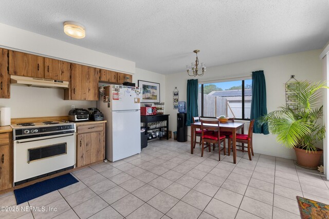 62 Atlantic Oaks Cir, Saint Augustine, FL 32080 - kitchen with a textured ceiling, under cabinet range hood, an inviting chandelier, white appliances, and brown cabinetry