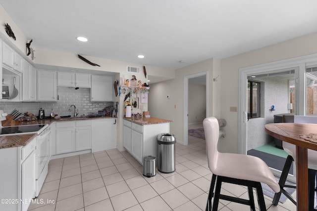 62 Atlantic Oaks Cir, Saint Augustine, FL 32080 - kitchen with white electric range oven, dark stone counters, decorative backsplash, white cabinets, and a sink