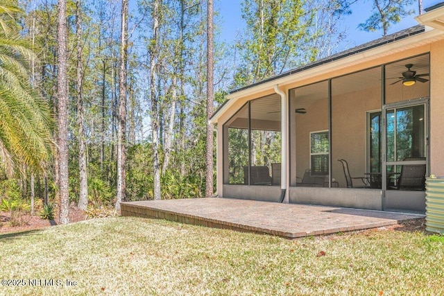 exterior space with a lawn, ceiling fan, and a sunroom