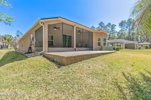 rear view of house with a patio, ceiling fan, a yard, and a sunroom