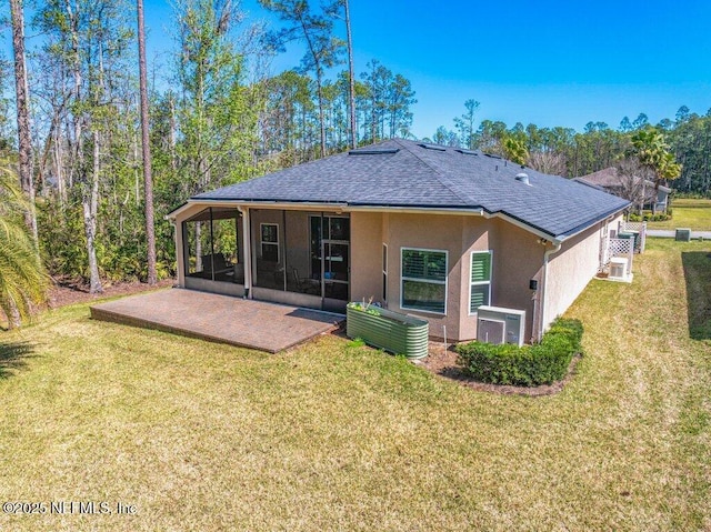 rear view of house with a patio, stucco siding, a sunroom, a shingled roof, and a yard
